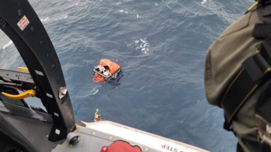 Fishermen in life raft signal to US Coast guards with flare
